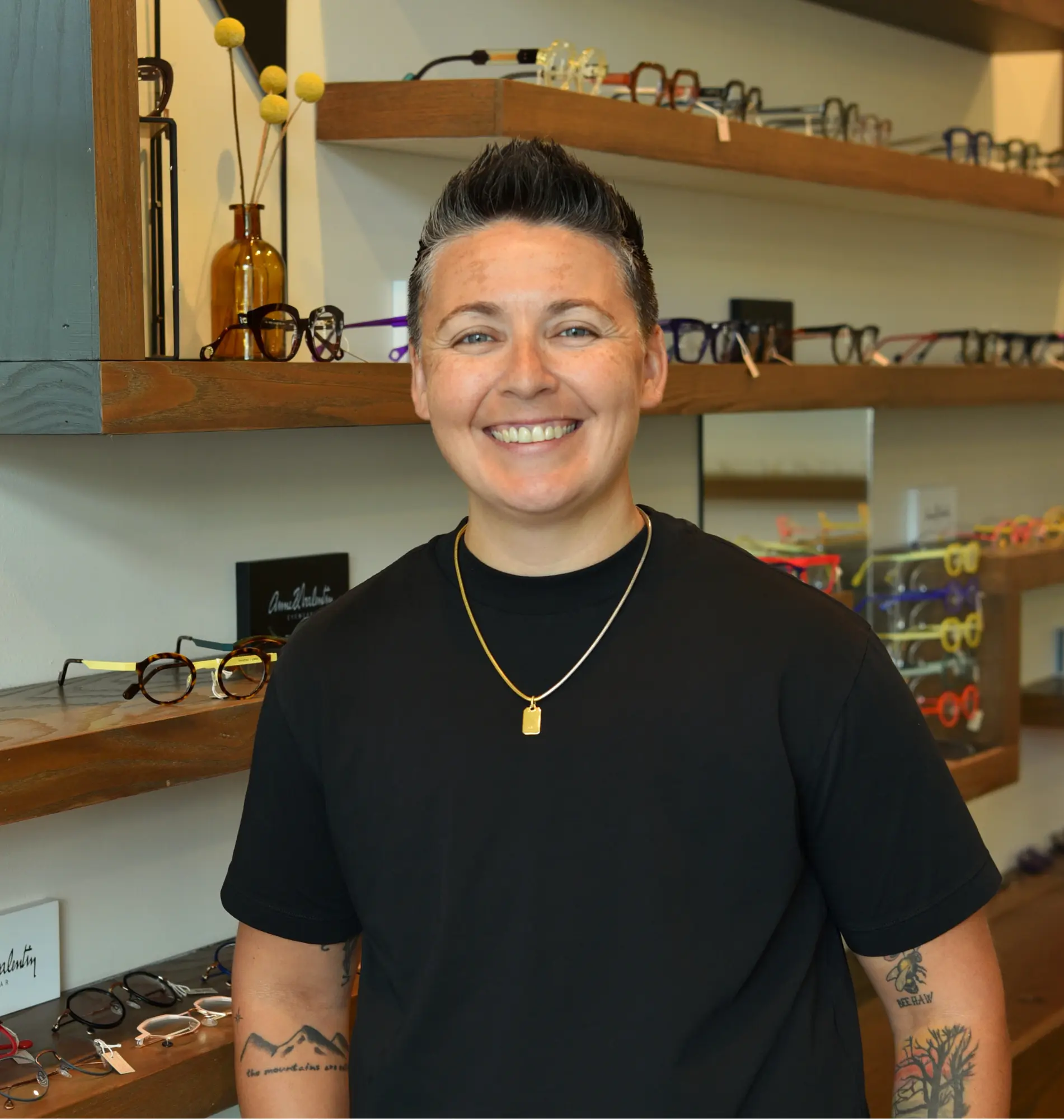 Chrissy, lead optometric technician, smiling in front of the frame wall