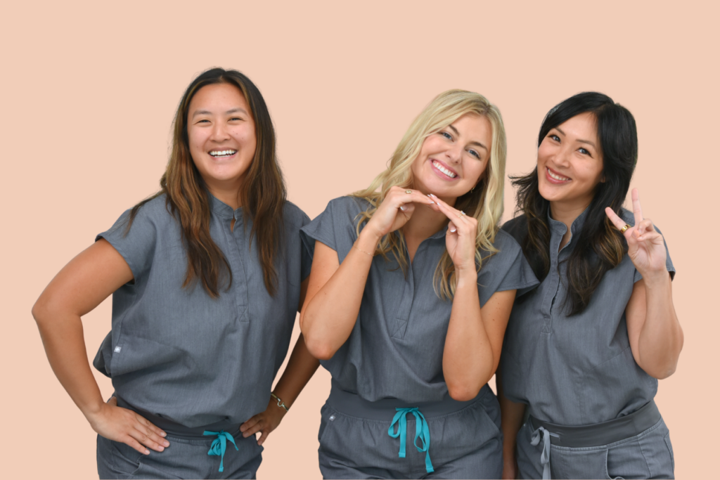 The three Look + See optometrists smiling together in gray scrubs