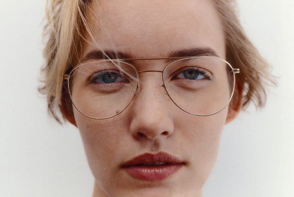 Woman with blonde hair wearing thin MYKITA aviator-style glasses