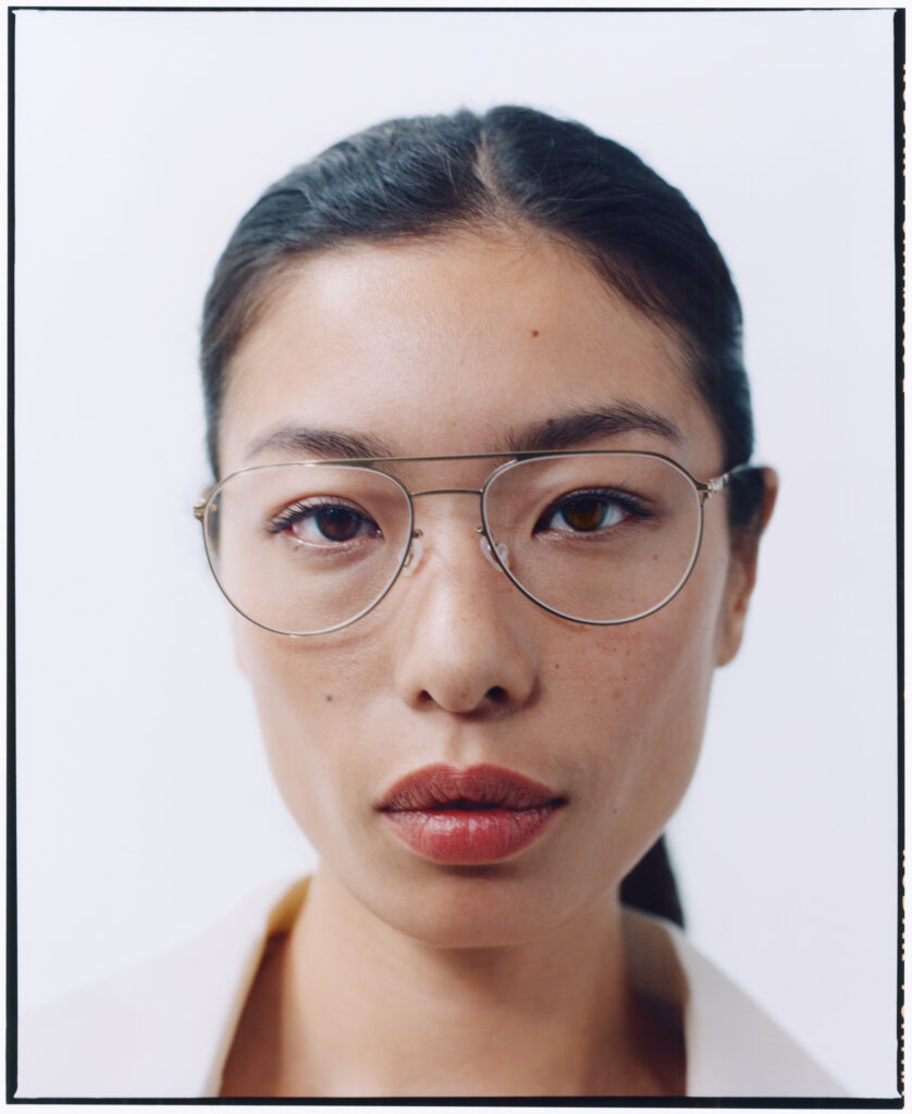 Woman with dark hair pulled back wearing MYKITA wire-frame glasses