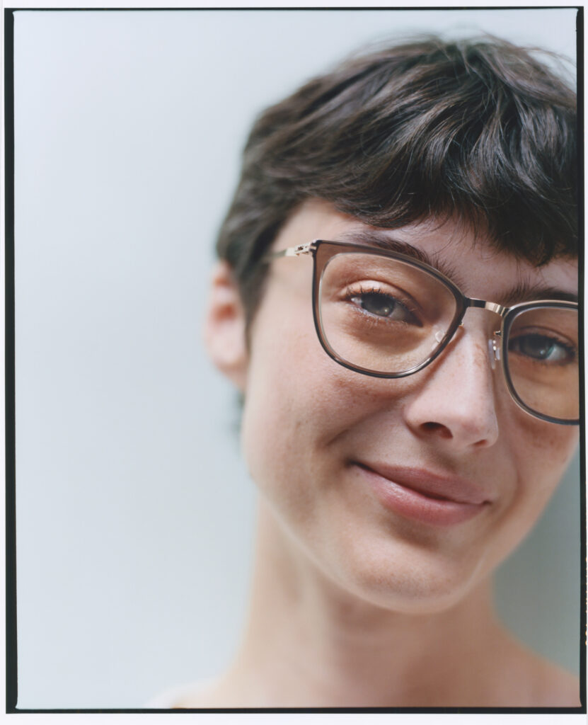 Smiling woman with short dark hair wearing MYKITA acetate glasses